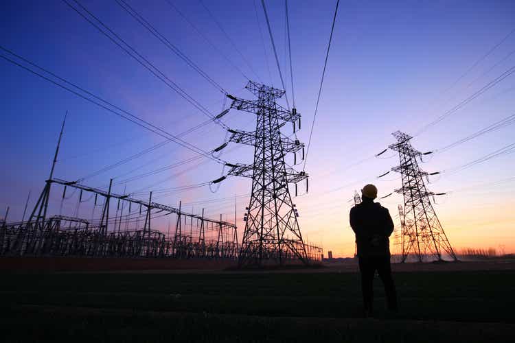 Electricity workers and pylon silhouette