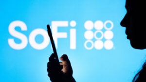 Silhouette of a person holding a mobile phone with the SoFi (SOFI) logo shown in the background