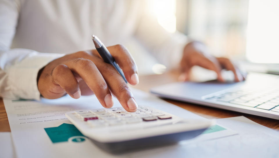 Finance, accounting and fintech, a man at a computer and a calculator working out his business budget strategy.  Businessman at his office desk, laptop, managing money and financial investment online.