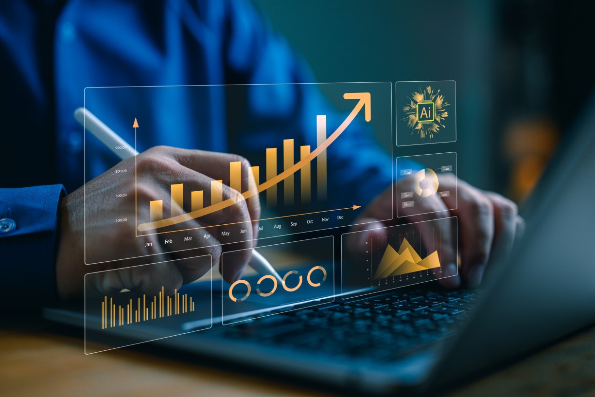 Close up of man's hands typing on laptop computer keyboard with a gold image overlaid that shows bar graphs, pie charts and AI logos.