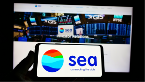 Person holding a mobile phone with Singapore technology conglomerate Sea Ltd logo on screen in front of company web page Focus on phone display.  SE Shares