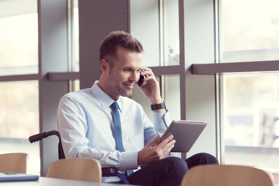 An investor looks at something on a tablet while talking on the phone.