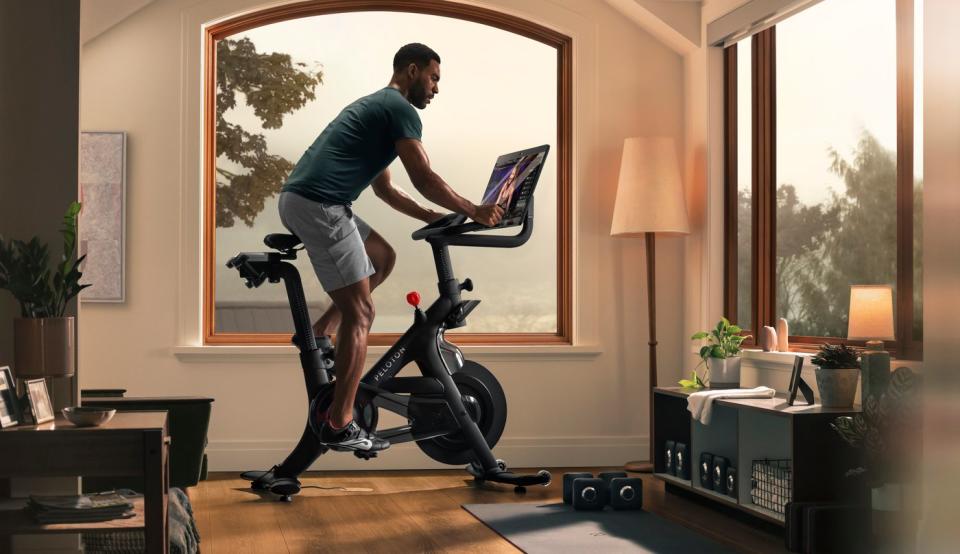 Person riding a Peloton bike in a living room.