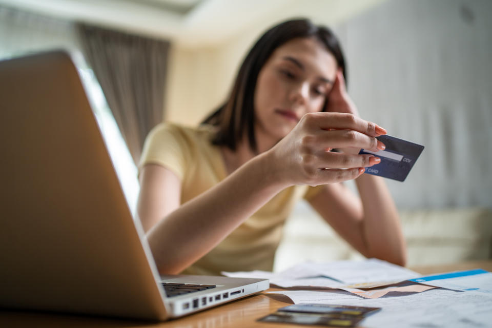 Uma jovem asiática deprimida sente-se preocupada com problemas financeiros em casa.  Uma jovem desesperada e estressada que parece frustrada com a papelada e as contas pensa em dívidas de dinheiro, perda orçamentária, falência em casa.