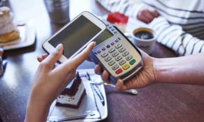 a person holding a smartphone over a check out scanner representing payments stocks to buy