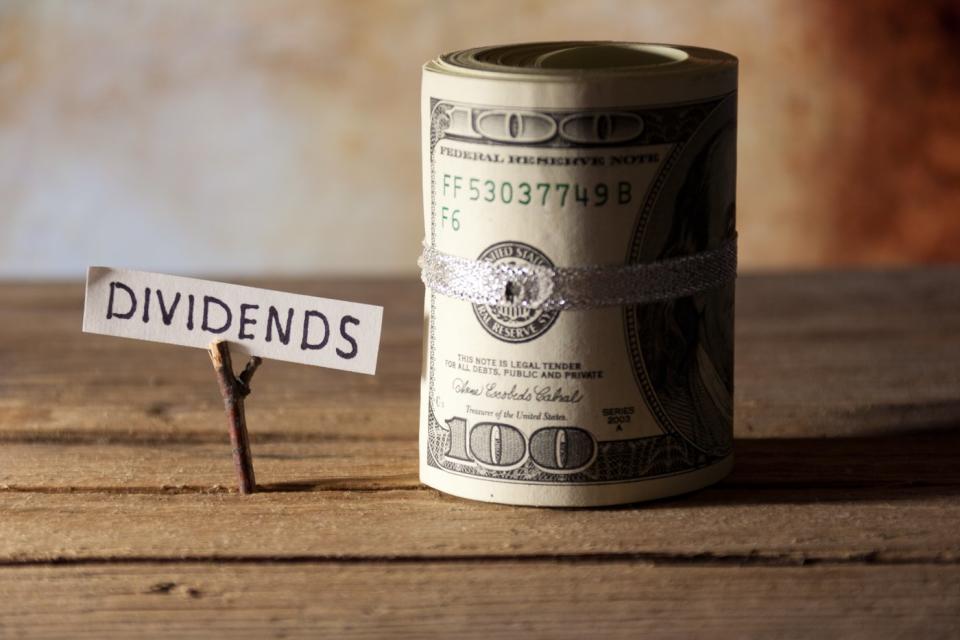 A sign with the word dividends next to a roll of money.