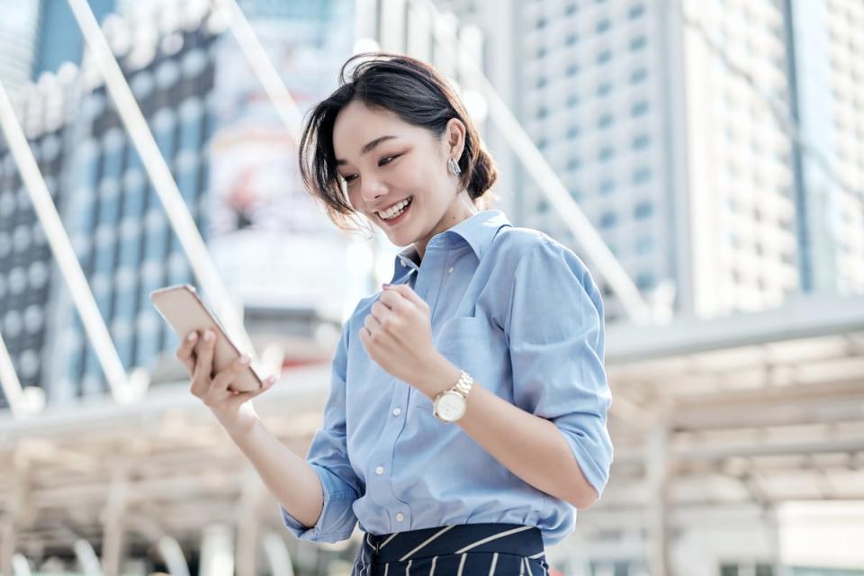 A person clenching his fist and smiling while looking at his cell phone.