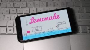 The Lemonade stock logo appears on your smartphone above your computer keyboard.