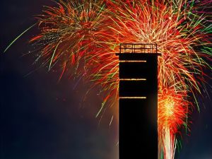 fireworks burst red, yellow, green and orange in the sky behind one of Delaware's World War II fire control towers.