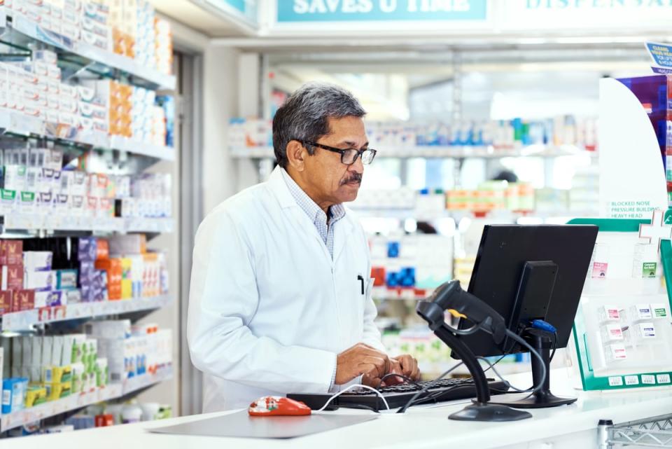 A pharmacist working on a computer on a counter.